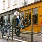 MATE X EVO kaufen: Leistungsstarkes Elektro-Klapprad im sportlichen Action-Einsatz mit Fahrer in einer städtischen Kulisse.