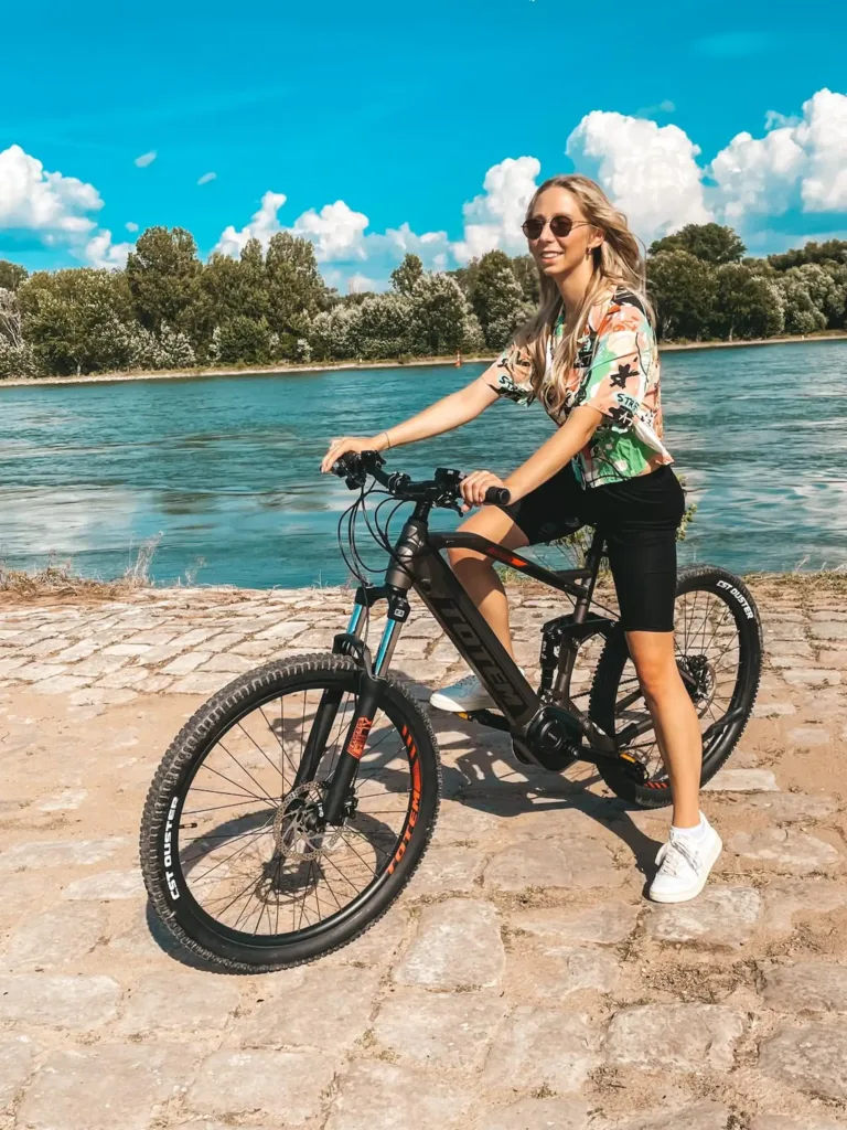 Mädchen auf einem TOTEM Carry E-Mountainbike in Grau neben einem Fluss – modernes E-Bike für Freizeit und Outdoor-Abenteuer, ideal zum E-Bike kaufen