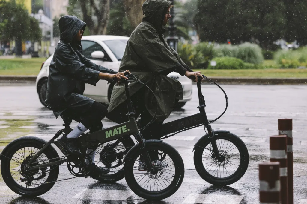 Mann und Junge fahren mit MATE E-Bikes Fusion durch die Stadt bei Regen