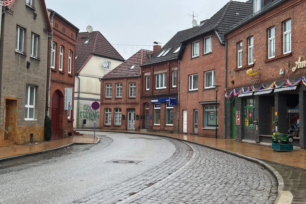 E-Bikes kaufen in Crivitz: Kopfsteinpflasterstraße in der Altstadt von Crivitz mit historischen Klinkerhäusern und Geschäften an einem bewölkten Tag.