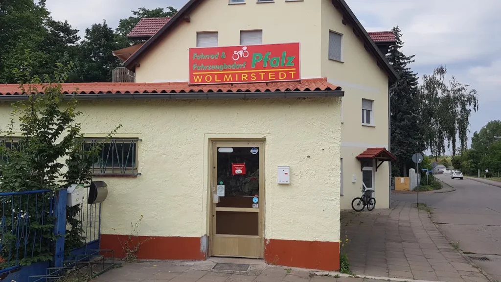 E-Bikes kaufen in Wolmirstedt – Fahrrad- u. Fahrzeugbedarf Pfalz: Die Außenansicht des Fahrradgeschäfts mit dem markanten roten Schild über der Eingangstür.