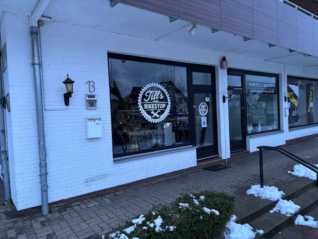 E-Bikes kaufen in Malente – Till's Bikestop: Die weiße Klinkerfassade des Fahrradladens in der Bahnhofstraße mit dem runden Werkstatt-Logo im Fenster.