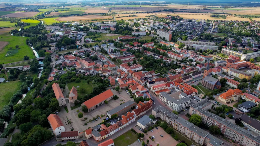 E-Bikes kaufen in Wolmirstedt: Luftaufnahme der Stadt Wolmirstedt mit der Schlossdomäne, historischen roten Dächern und der umgebenden grünen Landschaft.
