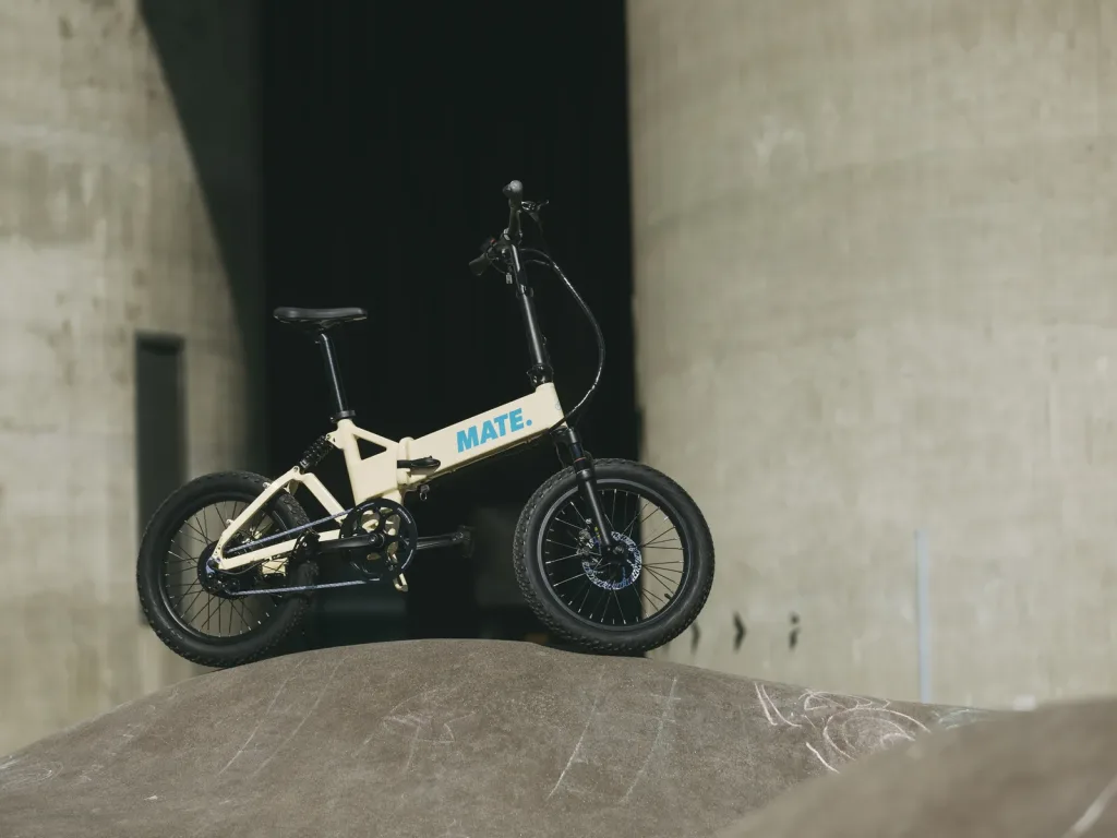 Stilvolles MATE E-Klapprad in Ivory Moon präsentiert in einer urbanen Kulisse aus Sichtbeton.