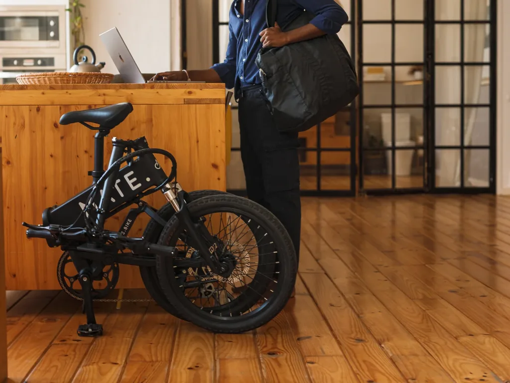 Kompaktes MATE City E-Klapprad im gefalteten Zustand in einer modernen Loft-Wohnung neben einer Holzkücheninsel.